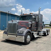 Large semi-truck parked on a concrete surface with a blue building in the background.