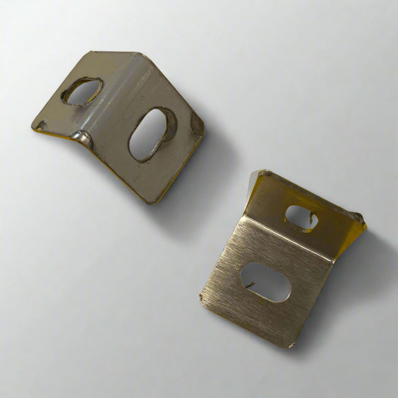 Two metal brackets on a yellow surface