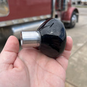 Black and silver knob held in a hand with a truck in the background