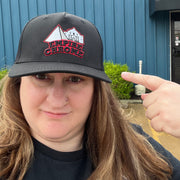 Person wearing black baseball cap in front of a blue background