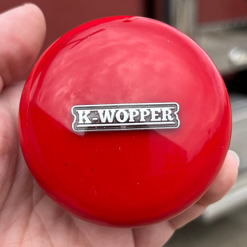 Red K-Wopper ball held in a hand with a blurred background